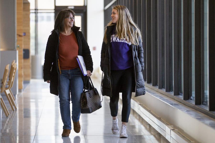 A student walks down a hallway with her mother.