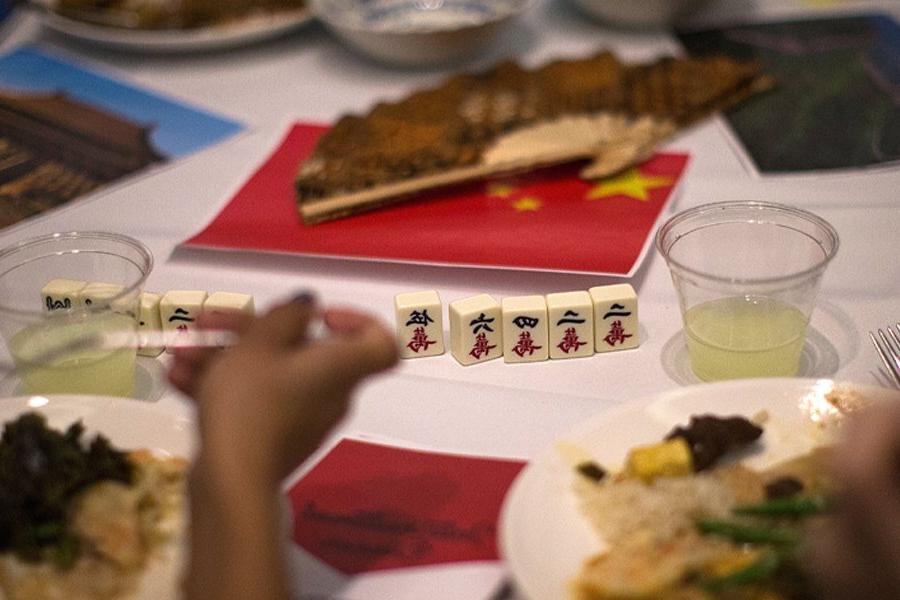 People eat a meal at a table with a small Chinese flag on the table.